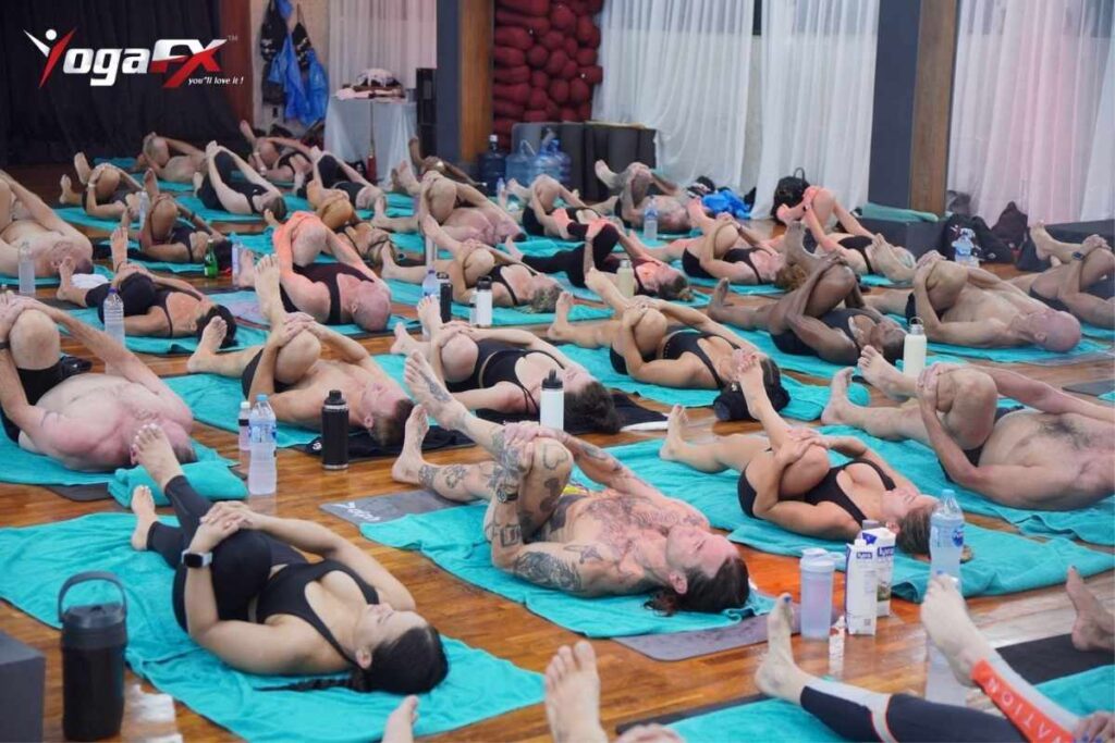 Full class practising the Bikram floor series on mats at the YogaFX studio in south Bali, the hot yoga room Ubud visitors drive south to reach