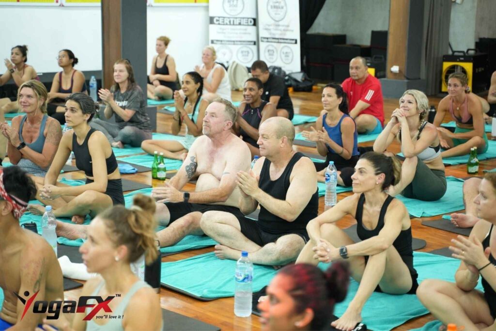 Students sitting and applauding on towels in a Bali hot yoga class, a relaxed view of a first class for anxiety